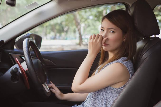 Driver holding her nose because of a bad smell in the car
