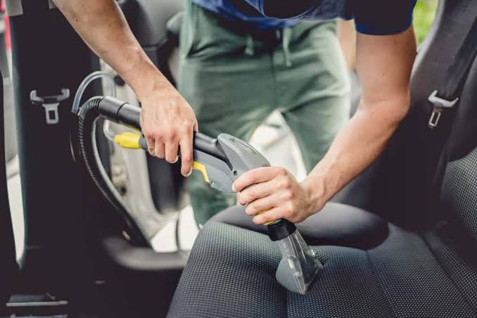 Technician extracting vomit residue from a fabric car seat